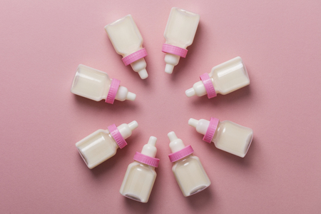 Baby bottles with milk on a pastel pink backgroundの写真素材