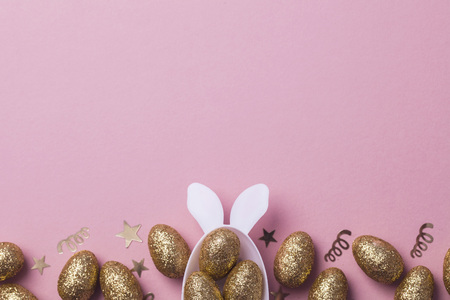 Gold glitter eggs in a white easter bunny egg shape with ears
