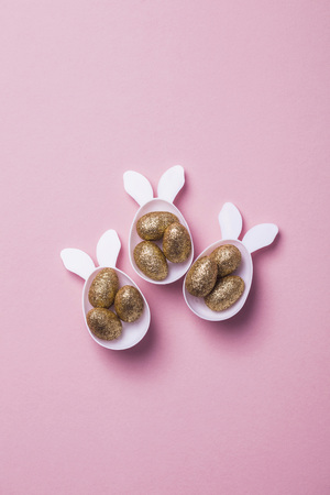 Gold glitter eggs in a white easter bunny egg shape with earsの写真素材