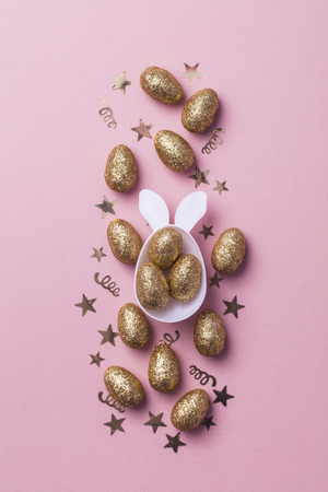 Gold glitter eggs in a white easter bunny egg shape with earsの写真素材