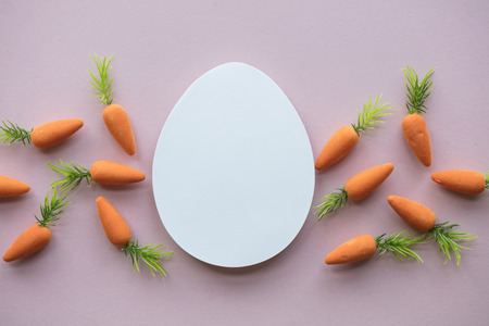 Easter composition with blank white easter egg and easter bunny carrots