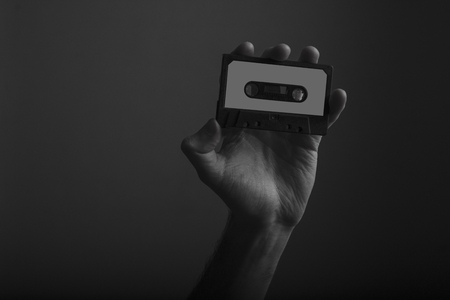Male hand holding vintage retro music cassette tapeの写真素材