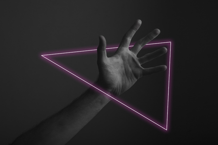 Male open hand gesture on a dark background with abstract neon light glowの写真素材