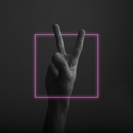 Male hand showing victory V hand sign with abstract neon light glowの写真素材