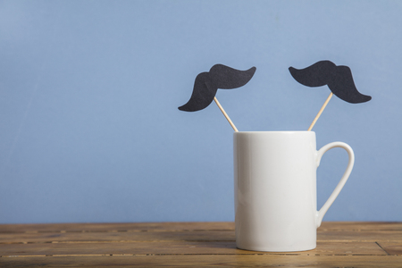 Fathers day coffee mug with a paper mustache against a blue backgroundの写真素材