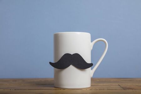 Fathers day coffee mug with a paper mustache against a blue backgroundの写真素材