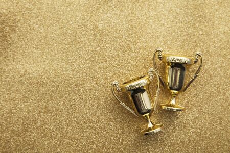 Gold winners achievement trophy on a gold glitter backgroundの写真素材