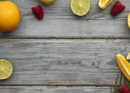Creative fruits flat lay. Orange, lime and raspberry on the wooden background