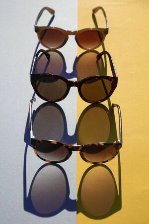 Fasionable summer sunglasses with long shadow on yellow and blue backgroundの写真素材
