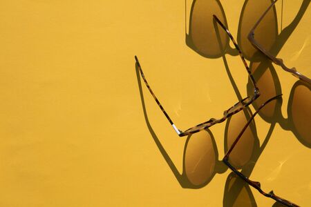 Sunglasses with long shadow on a brignt summer yellow backgroundの写真素材