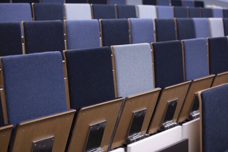 Rows of empty blue chairs in a conference room