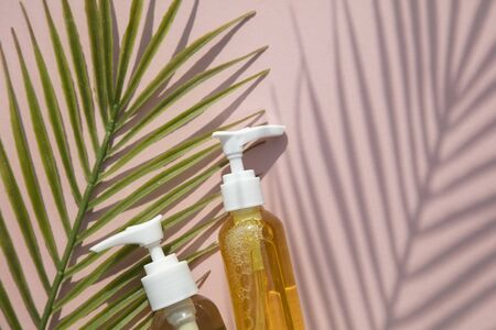 Natural cosmetic oil in a clear bottle with tropical leaf and shadow