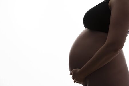 Pregnant woman with a baby bump silhouetted on a white background