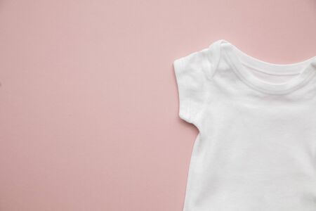 Cute baby white body suit layout on a pastel pink background