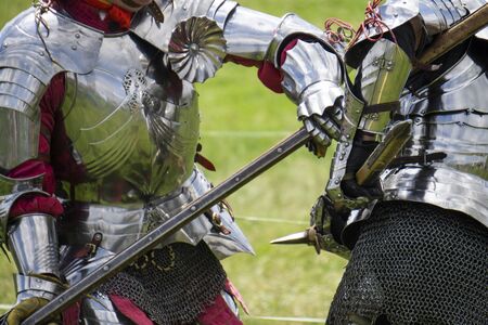 Two medieval knights in armour battle with weaponsの写真素材