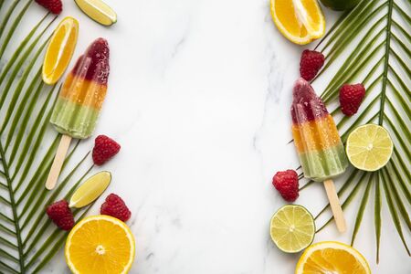 Summer ice lollies with fruit and a tropical palm leaf