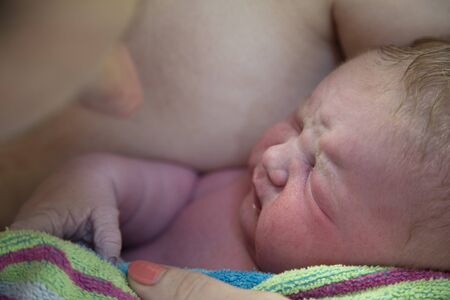 A newborn baby being embraced by their mother after being born