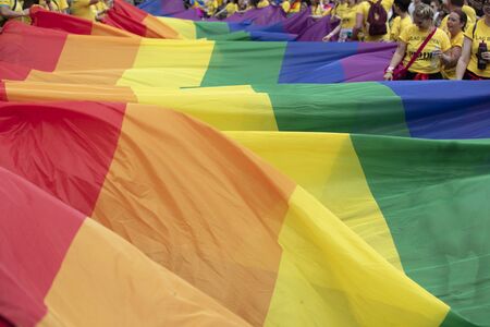 LONDON, UK - July 6th 2019: People hold a huge LGBTQ gay pride rainbow flag at the start of the...