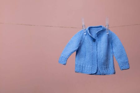 cute knitted new born baby jumper hanging on a clothes line against pink