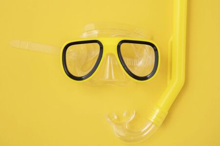 A yellow snorkel and diving mask on a yellow background. overhead lay flatの写真素材