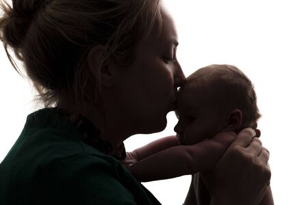 Silhouette of a mother holding her newborn babyの写真素材