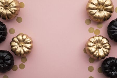 Gold and black pumpkins on pastel pink. Flat lay thanksgiving compositionの写真素材