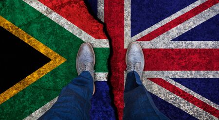 Business man stands on cracked flag of UK and South Africa. Political concept