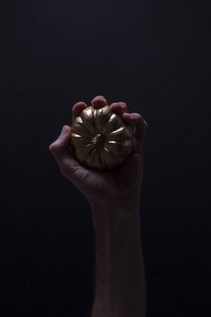 A male hand holding a golden pumpkin. Spooky halloween backgroundの写真素材