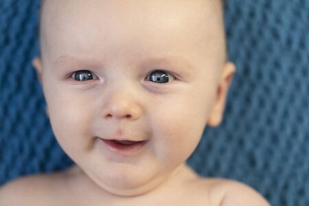 Close up of a happy smiling baby against a blue blanket backgroundの写真素材