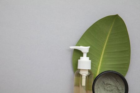 Organic natural cosmetic product with a green leaf on a grey backgroundの写真素材