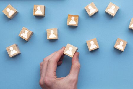 Hand choosing a wooden person block from a set. Employment choice conceptの写真素材