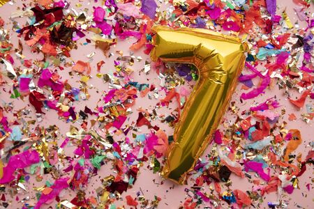 Number 7 gold birthday celebration balloon on a confetti glitter background