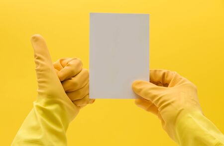 hand in a yellow cleaning glove holing a blank white card