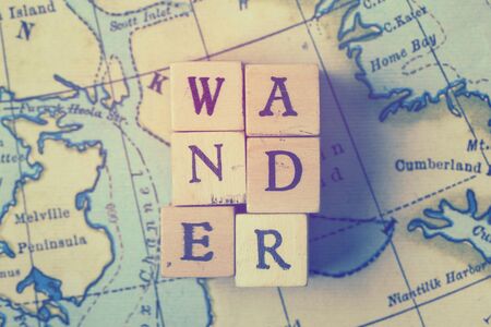 Wander word written in wooden blocks on a vintage travel mapの写真素材