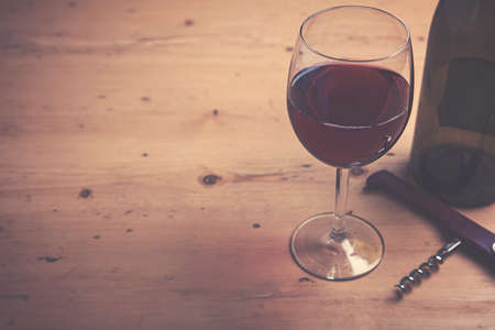 Glass of red wine with a bottle on a wooden backgroundの写真素材
