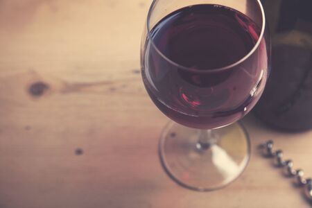 Glass of red wine with a bottle on a wooden backgroundの写真素材