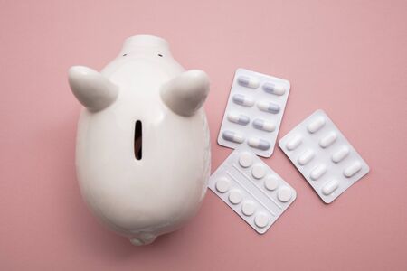 Healthcare cost. Money box piggy bank with packets of pills and tablet