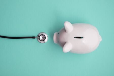 Cost of healthcare. Piggy bank money box with a medical doctors stethoscopeの写真素材