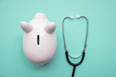 Cost of healthcare. Piggy bank money box with a medical doctors stethoscopeの写真素材