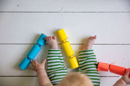 Overhead view of a baby playing with bright christmas cracker decorations
