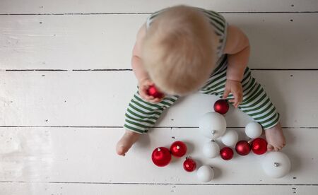 Overhead view of a little baby playing with red and white baubles decorationsの写真素材