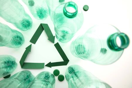 Green paper recycling symbol with empty plastic water bottles