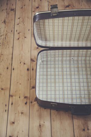 An open old vintage brown travel suitcase on a wooden floorの写真素材