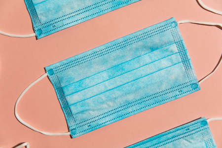 Blue surgical medical mask lay flat composition on a pink background