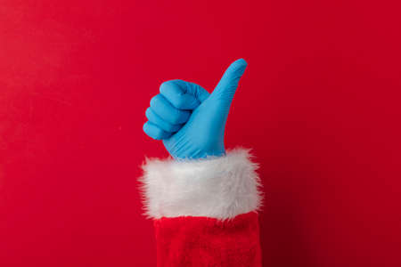 Santa hands wearing blue PPE protective gloves making thumbs up signの写真素材