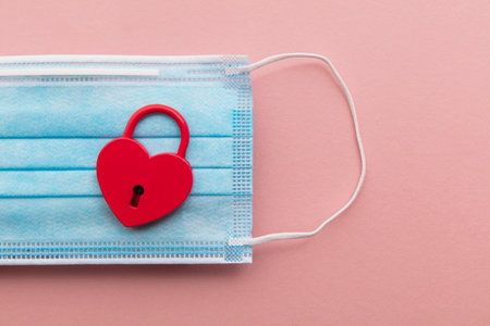 Love in Lockdown. Red heart shaped valentine padlock on a maskの写真素材