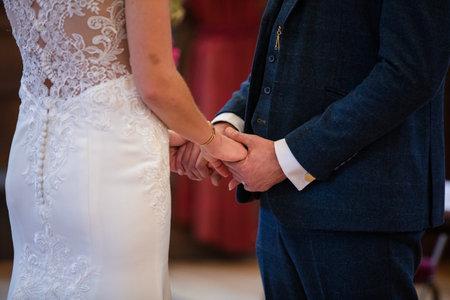 Close up of a bride and groom holding hands during wedding ceremonyの写真素材