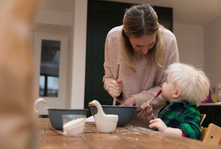 Mother and child having fun together in the kitchen baking cakes.の写真素材