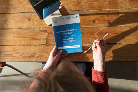 OXFORD, UK - February 2020: A woman reads the government Covid-19 home test kitのeditorial素材