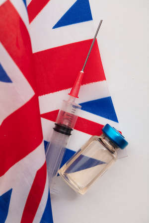 A medical vaccine syringe and vial bottle on a United Kingdom Union Jack flagの写真素材